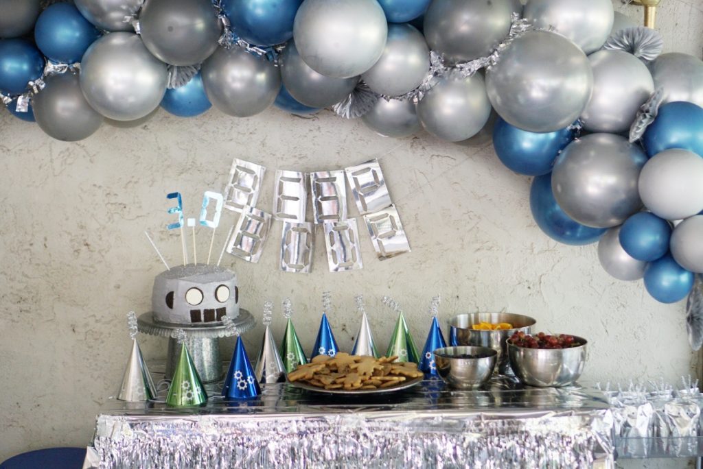 DIY Balloon Arches & Swags - Robot themed birthday party features a metallic silver and blue balloon arch with tinsel and gear embellishments. 
#partyballoons
#DIYBalloons
#DIYBalloonArch
#DIYBalloonSwag
#BalloonArch
#BalloonSwag
#RobotParty
#RobotBirthdayParty
#Partyideas
